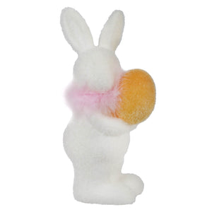 White plush bunny holding a yellow egg with a pink bow around its neck.