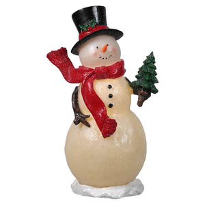 Cream-colored lighted merry snowman figurine with top hat scarf and red accents holding a tree decoration