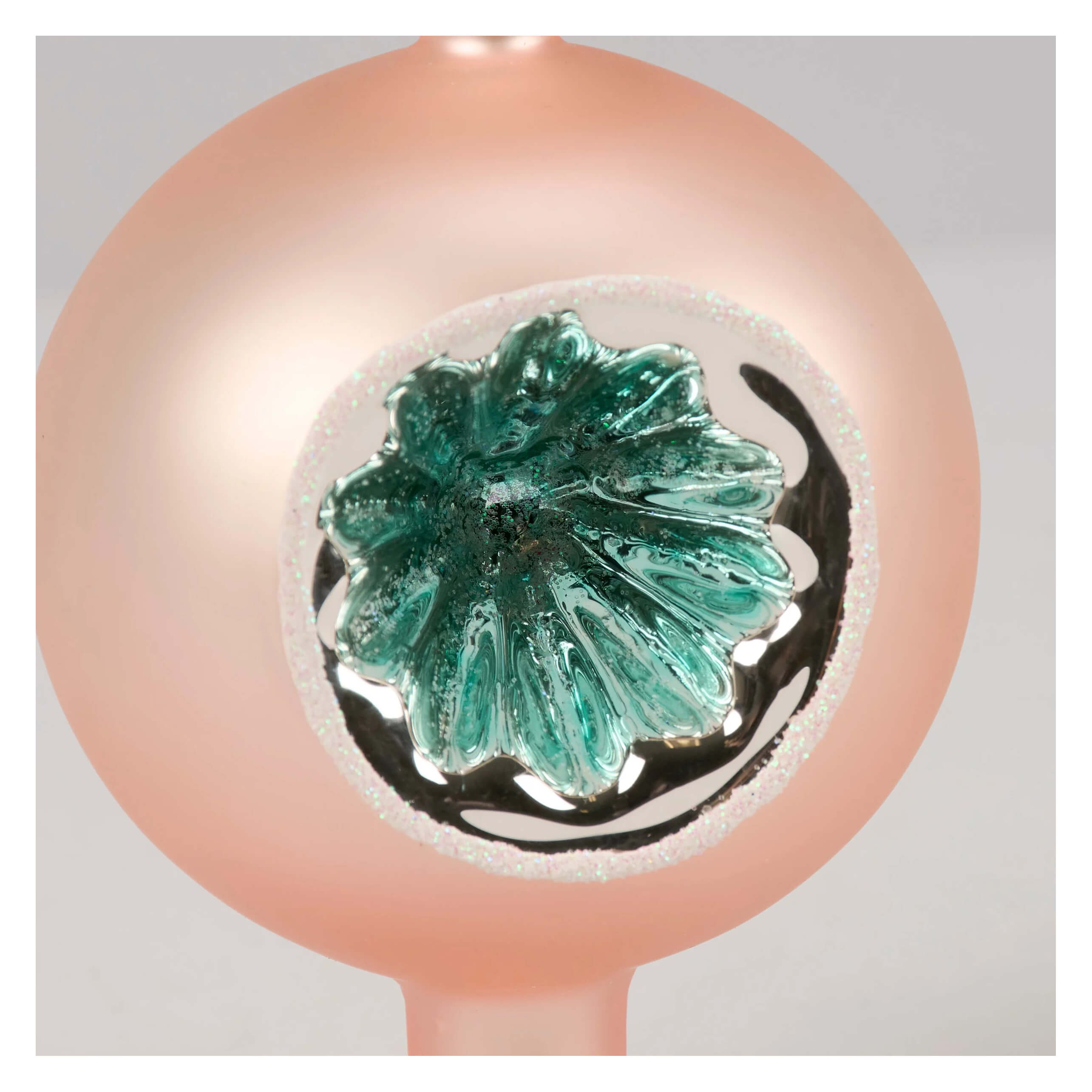 A translucent peach pink glass tree topper with a teal flower design and silver glitter from kathy christmas collection