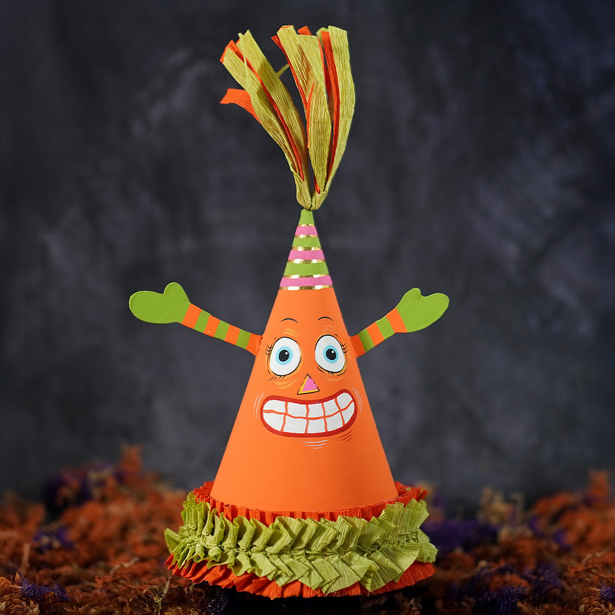 Orange paper spooky pumpkin party favor cone box with green fringe striped arms and colorful tassel top for vintage halloween tabletop decor
