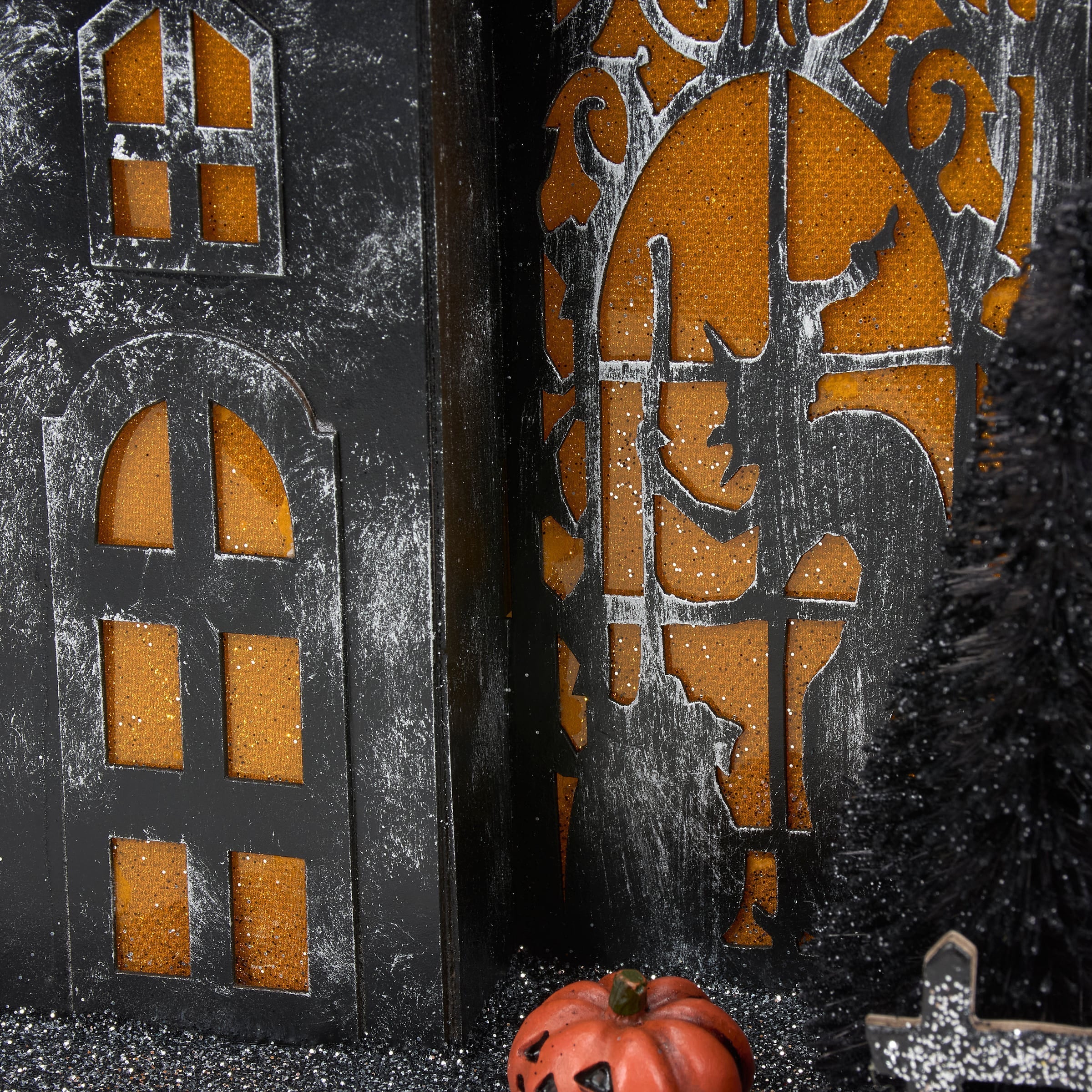Black halloween-themed lighted haunted house sitter with orange glittery windows and a rustic finish for dead & breakfast decor