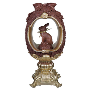 Brown resin 12 inch egg pedestal with gold trim and vintage easter bunny figural decor inside a window display