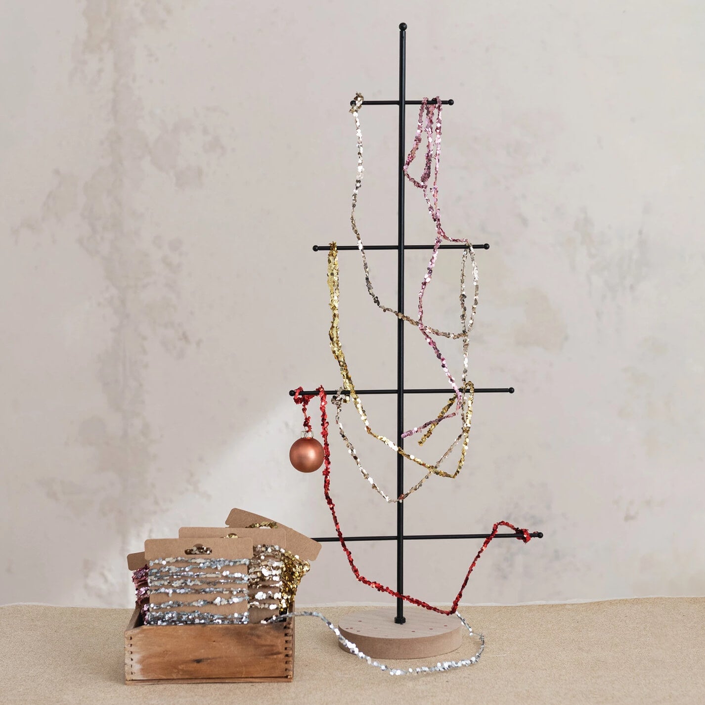 Black metal jewelry tree holding colorful sequined necklaces with 120 inch gold finish string glitter garland on kraft card