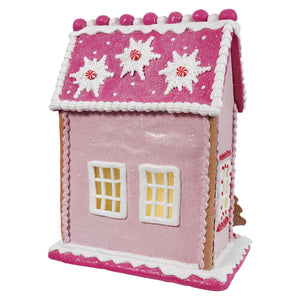 A 13 inch lighted pink gingerbread house by raz imports christmas with glitter, white icing trim, and candy cane snowflakes