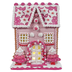 A 13 inch lighted pink gingerbread house with white icing snowflakes red candy and glittery trees by raz imports christmas