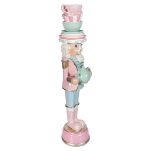 Pastel resin dessert toy soldier balancing teacups in pink and mint green holding a teapot with stacked cups