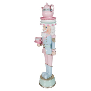Pastel resin dessert toy soldier figurine in pink and blue holding a teacup with an ornate tea set on top
