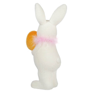 White bunny figurine wearing a pink bow and holding an orange egg.