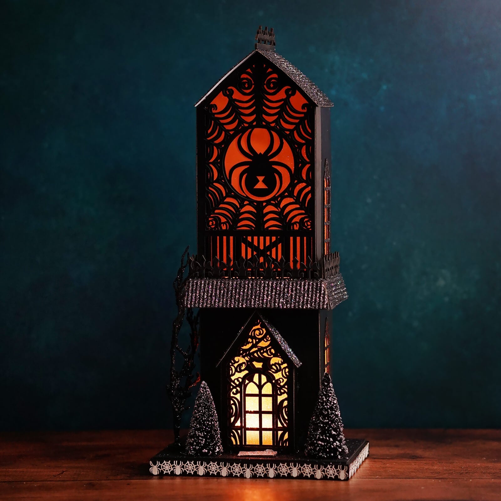 Black halloween-themed lighted spider haunted gothic house lantern with glowing orange and yellow lights for haunted village scene