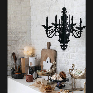 Black ornate hanging mdf interlocking chandelier with bats and spiderwebs above halloween themed counter display