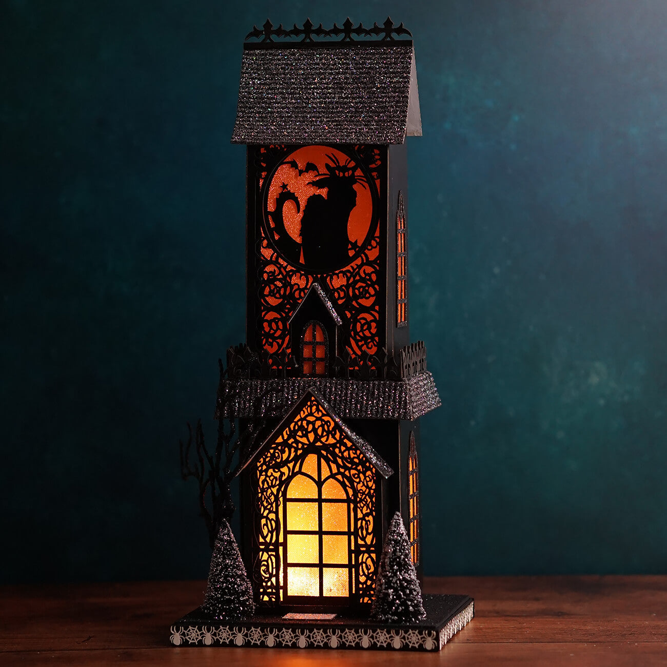 Black halloween-themed decorative lantern with glowing orange light and glittery roof for lighted haunted village scene