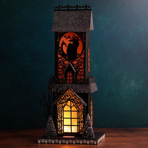 Black halloween-themed decorative lantern with glowing orange light and glittery roof for lighted haunted village scene