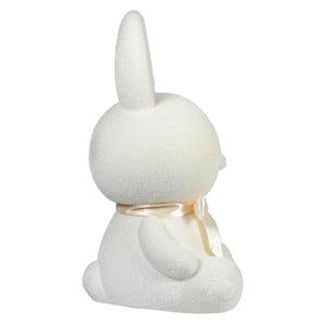 White plush bunny with a cream-colored ribbon around its neck.