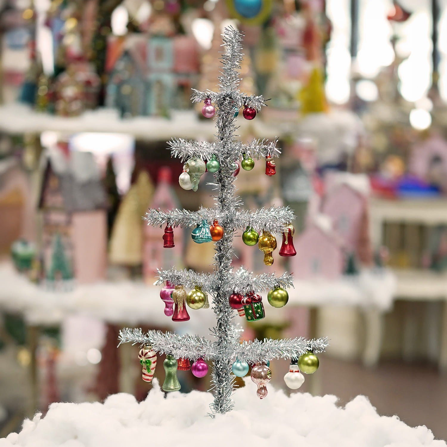 A 24 inch cody foster tinsel tree in silver with colorful christmas memories glass ornaments and candy cane decorations