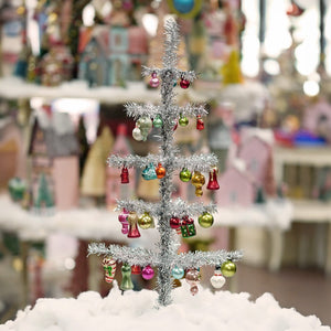 A 24 inch cody foster tinsel tree in silver with colorful christmas memories glass ornaments and candy cane decorations
