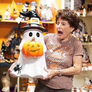 White ceramic large ghost holding lighted pumpkin with black witch hat and spider decoration spreading holiday cheer