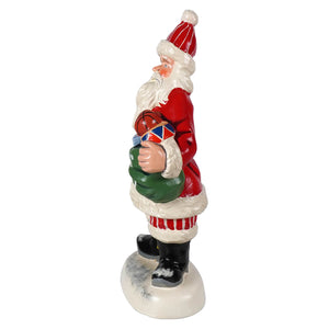 Red and white painted american santa figurine holding basketball and green sack on snowy base from vaillancourt folk art