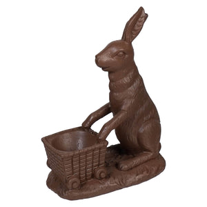 A 6.25 inch chocolate bunny sitting upright with front paws on a miniature wicker cart vintage easter bunny figural decor