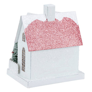 A festive white lighted fenced house sitter ornament with glittery pink roof and snow-dusted details and christmas tree