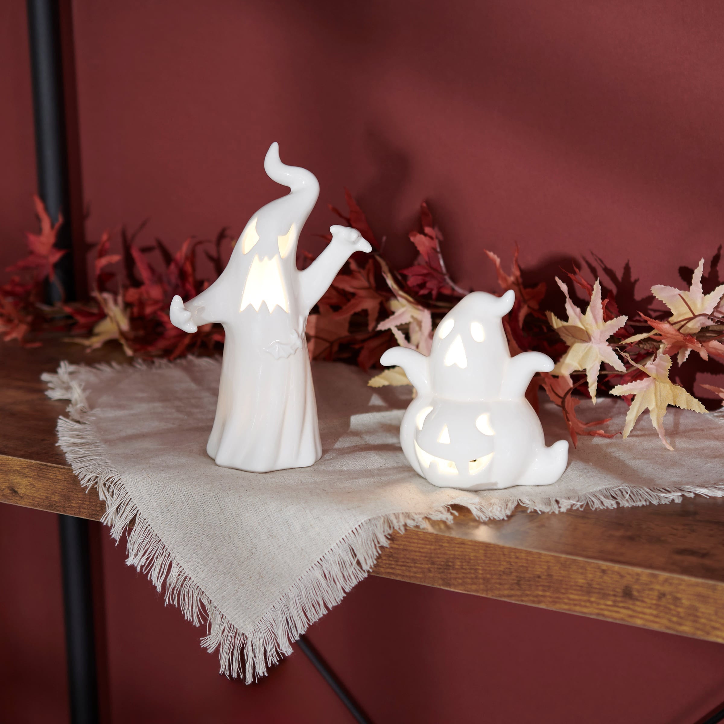 White ceramic halloween ghost figurine and pumpkin lanterns with glowing cut-out windows for spooky decor