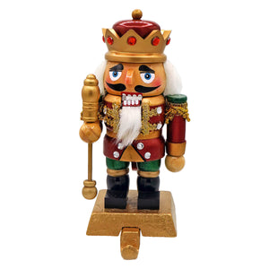A festive red and gold nutcracker king stocking holder with white beard holding a golden staff for holiday decor