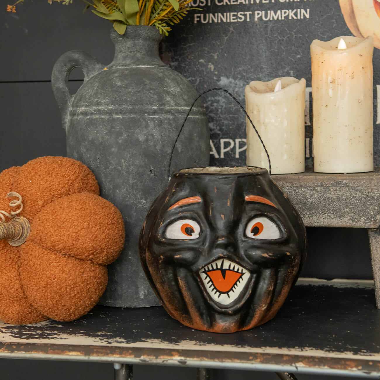 Grinning black Halloween pumpkin bucket with orange eyes and mouth.