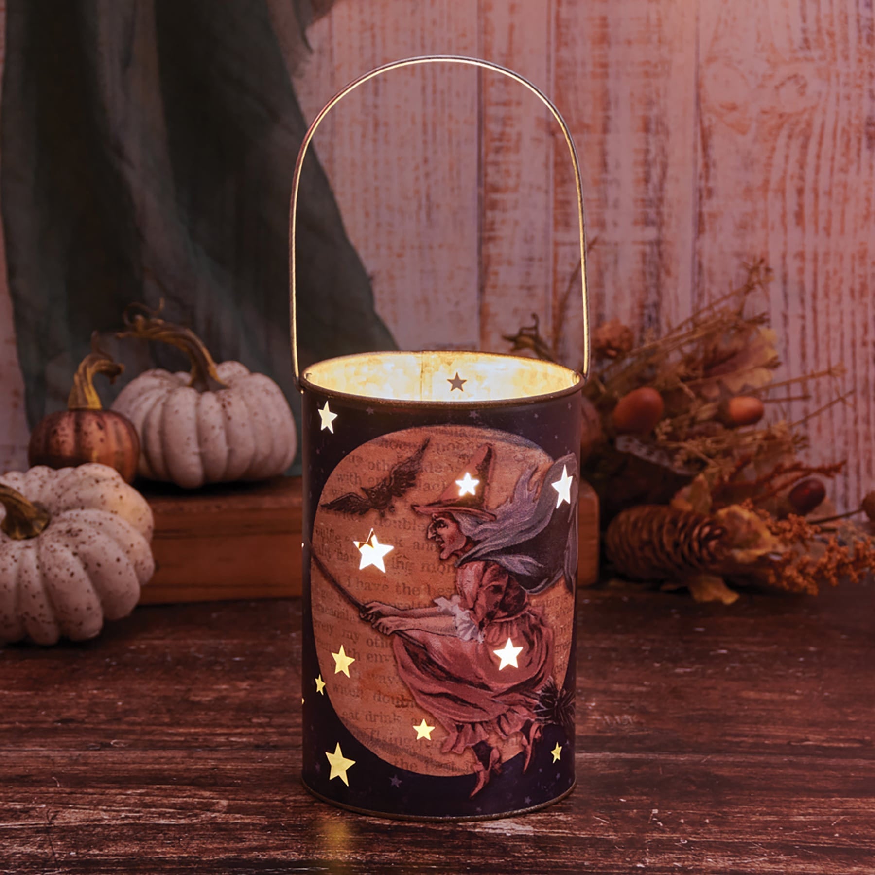 A black metal midnight witch lantern with a gold handle featuring halloween lights and decor with vintage witch design