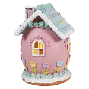 A 7 inch pink lighted easter bunny house with pastel colors, blue roof, white trim, and colorful floral decorations