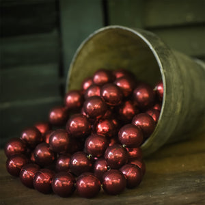Shiny red metallic jumbo red bead ornaments spilling from rustic metal bucket for ragon house garland decor