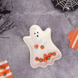 White ceramic ghost tray with black eyes smiling face holding miniature orange pumpkins perfect for halloween décor