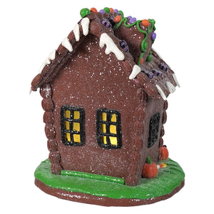 A glittery brown 9.5 inch lighted halloween gingerbread house with white icing drips and colorful candy roof decor