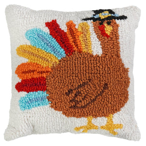 A 9 inch colorful thanksgiving pillow with a plush brown turkey figural decor and rainbow feathers wearing a black hat