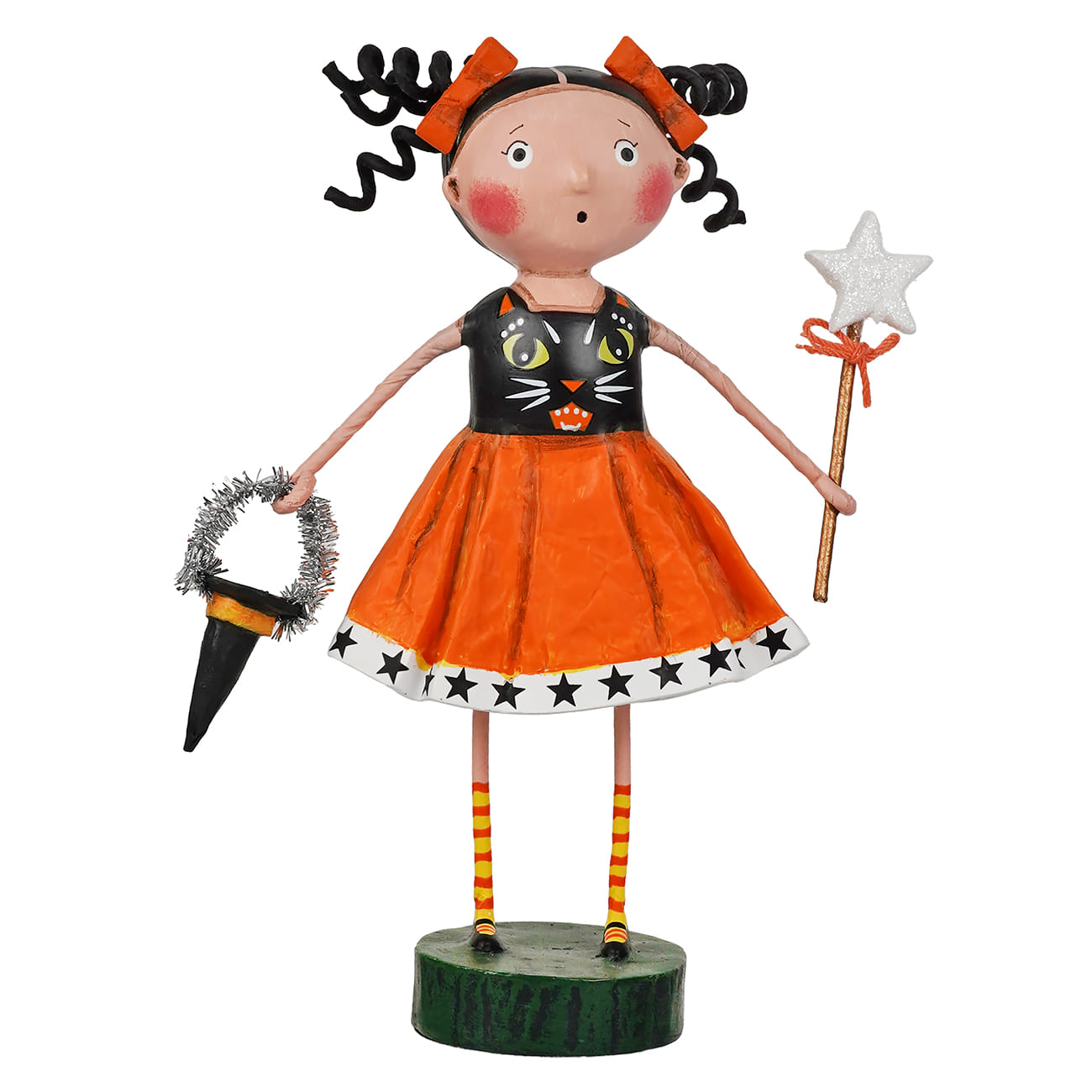 A stylized Halloween doll figurine with a round green base, wearing an orange skirt, black cat-print bodice, striped legs, and orange hair bows, holding a broom and a star wand on a plain white background.