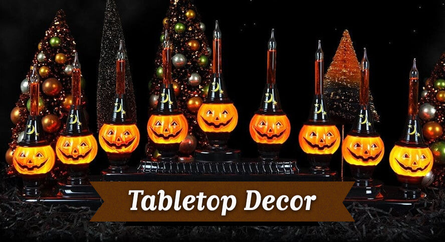 Halloween tabletop décor featuring illuminated jack-o'-lantern candelabra and vintage-inspired bottle brush trees.