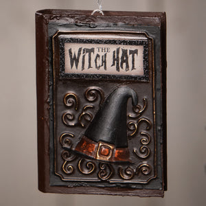 Dark brown bethany lowe witch hat book ornament with black hat, orange-brown belt, gold buckle, and ornate metal frame