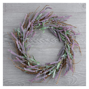 A rustic lavender wreath with dried purple flowers and green leaves on a natural vine base for spring hanging decor