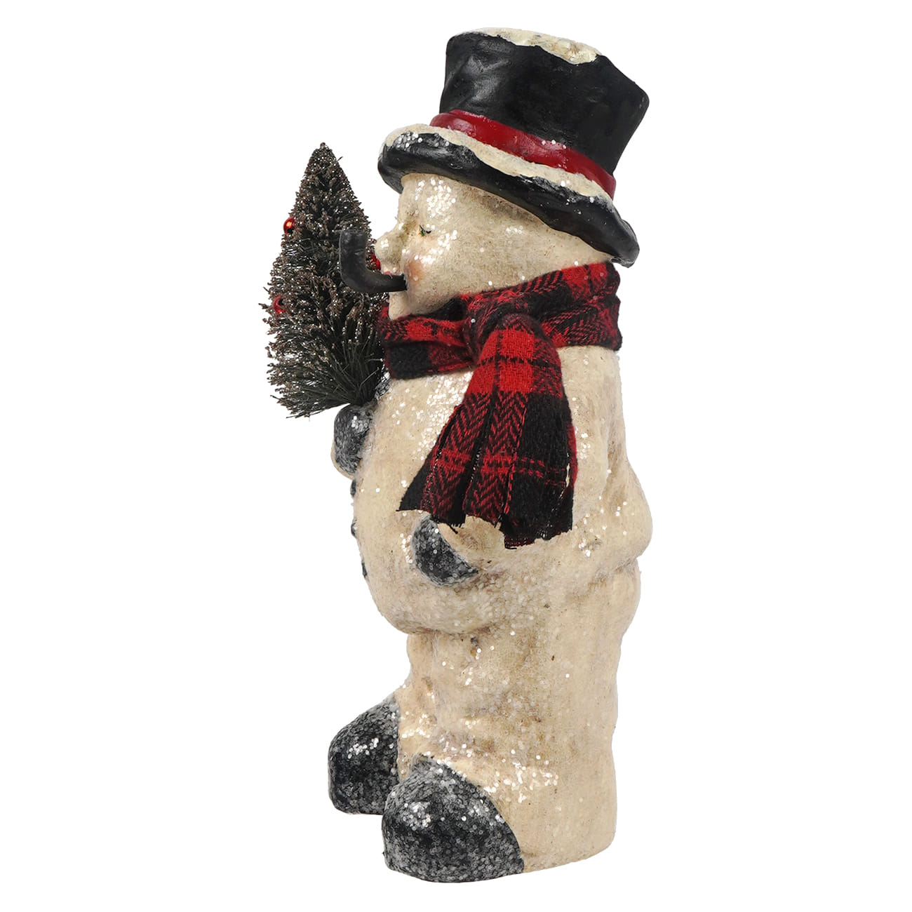 Side view of snowman figurine with a glittery beige body, a black top hat with a red band, a red and black plaid scarf, and black mittens and boots, holding a small black Christmas tree on a white background.
