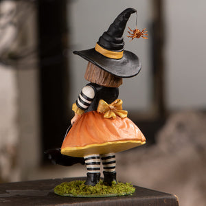 A whimsical emery witch with a black and gold hat, orange skirt, and striped leggings perfect for halloween witches decor