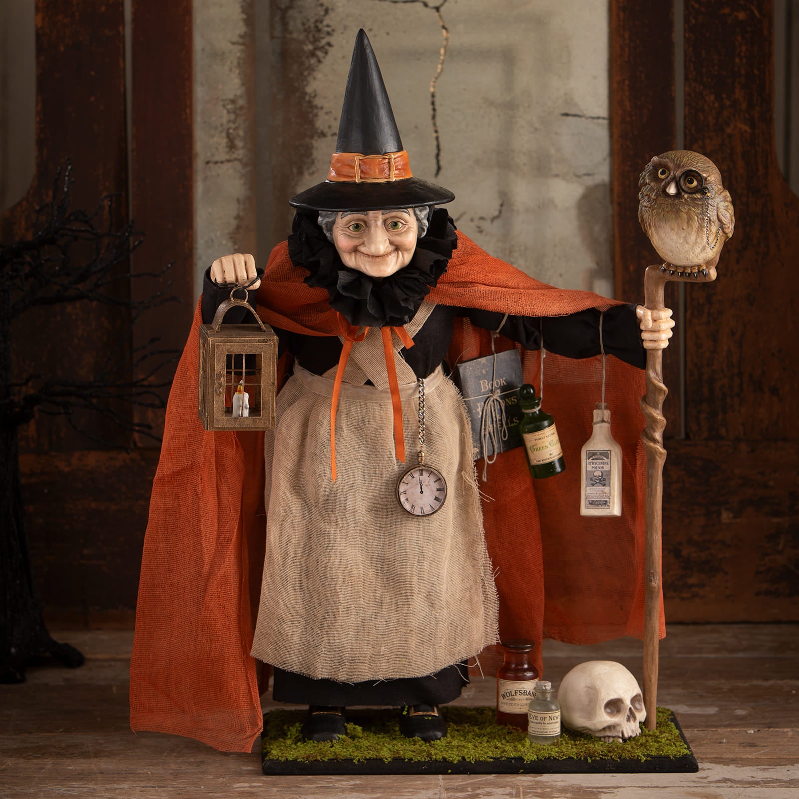 A detailed halloween witches figurine potion peddler zelda witch with black hat orange cape burlap apron holding lantern and owl staff