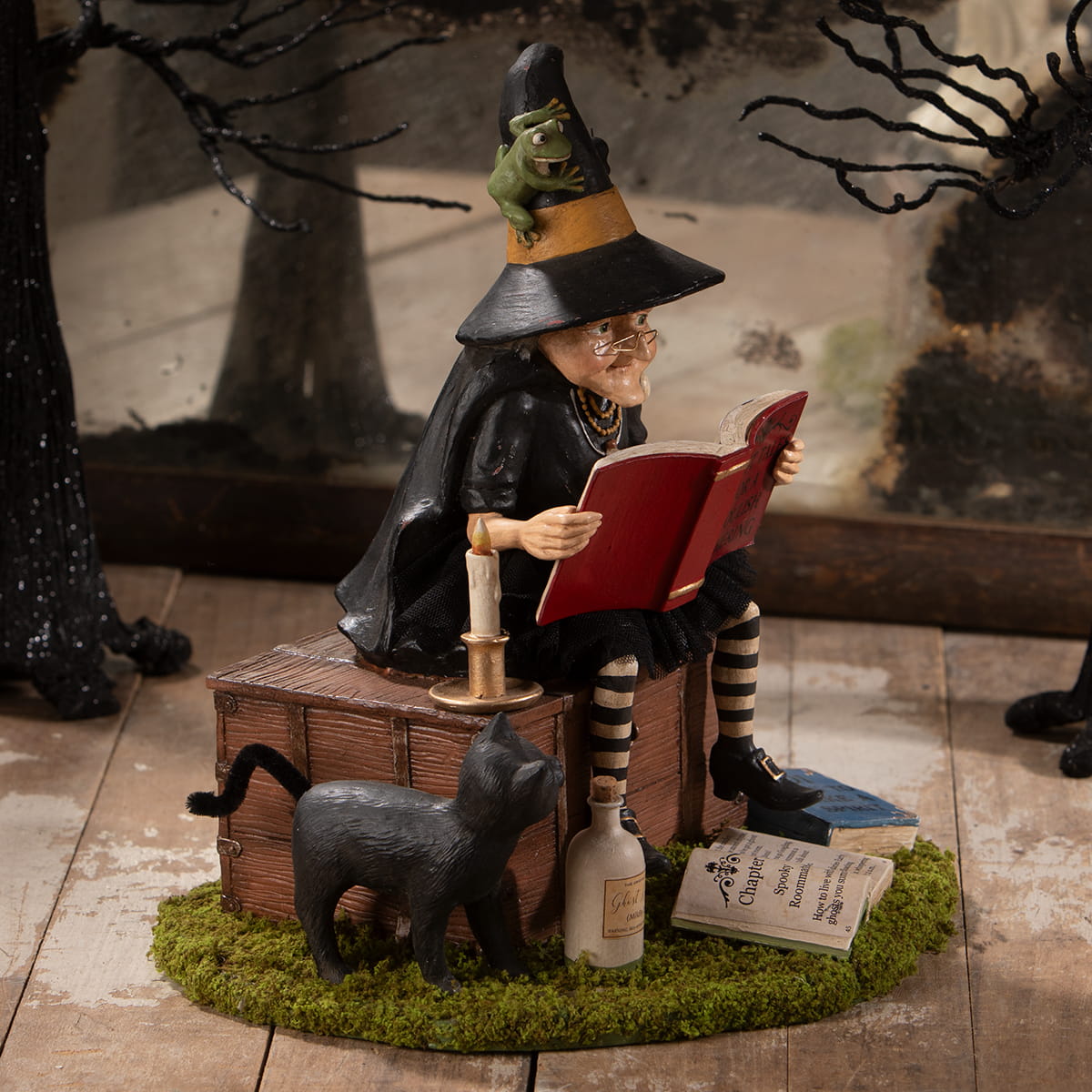 A whimsical ghost stories witch figurine with halloween witches decor, black orange hat, glasses, striped stockings, and frog on head