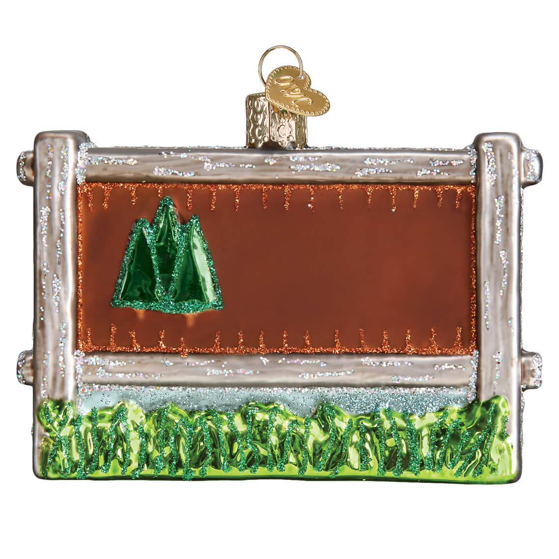 Silver-framed glass acadia national park ornament with glittery green pine trees and sparkling grass against orange sky