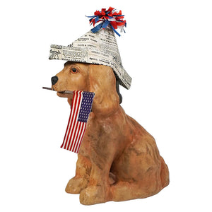 A tan ceramic americana puppy dog figurine wearing a patriot paper hat and holding an american flag in its mouth