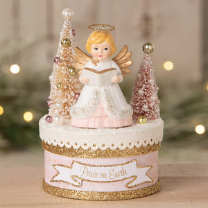 Delicate bethany lowe angel figure with blonde hair and gold wings on a holiday box reading peace on earth