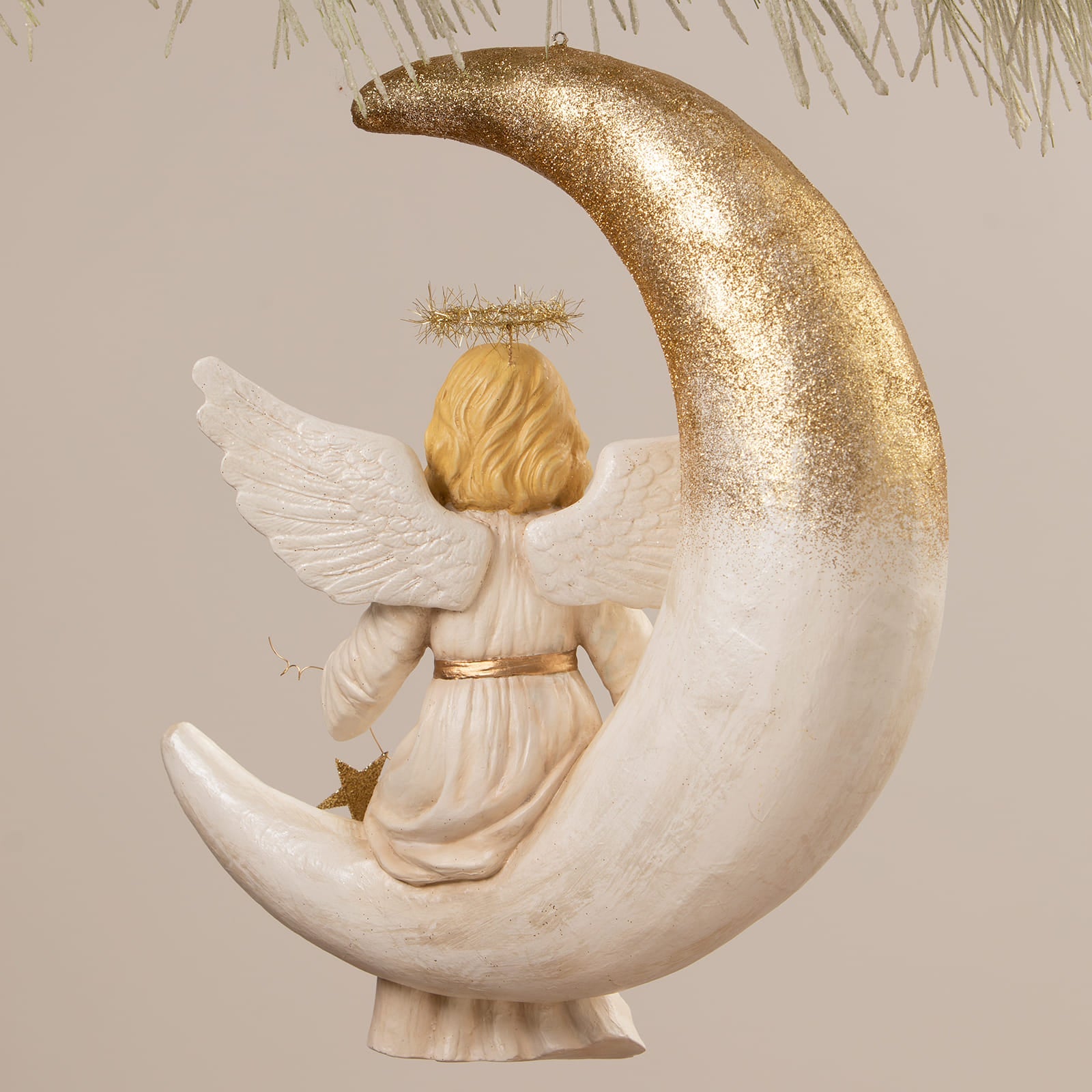 A delicate bethany lowe angel figure with blonde hair and white wings seated on a glittering gold to white moon