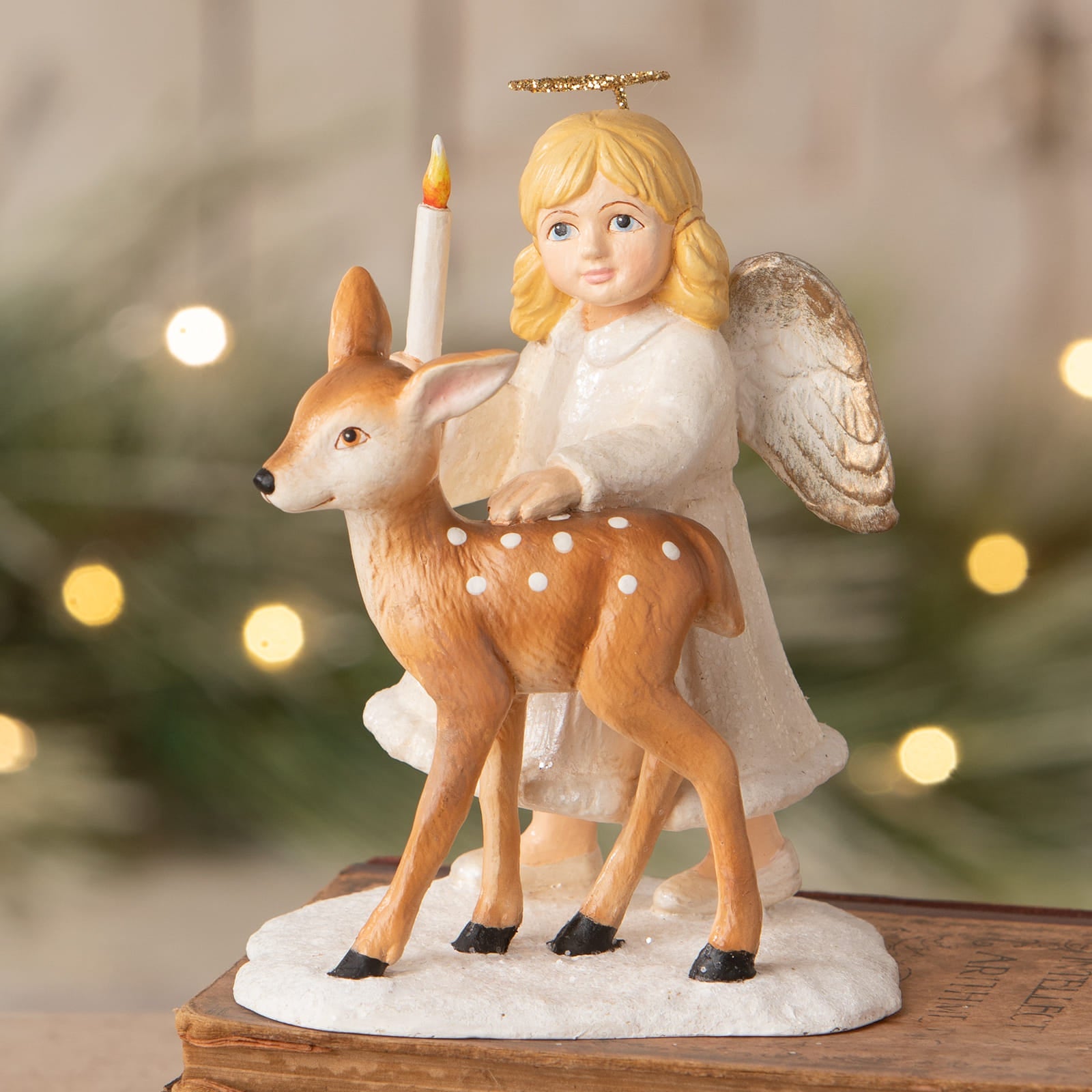 A delicate bethany lowe ariel angel with blonde hair holding a candle beside a brown spotted deer on snowy base