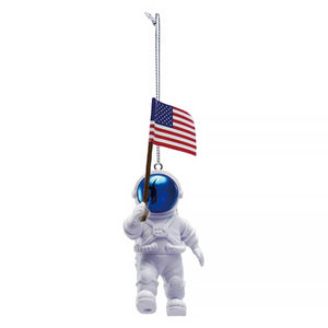 White astronaut ornament with reflective blue helmet holding an american flag ornament on a chain