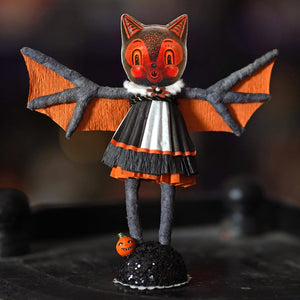 A charming bat girl figure with orange and black paper-craft bat wings, white ruffled collar, and layered dress details