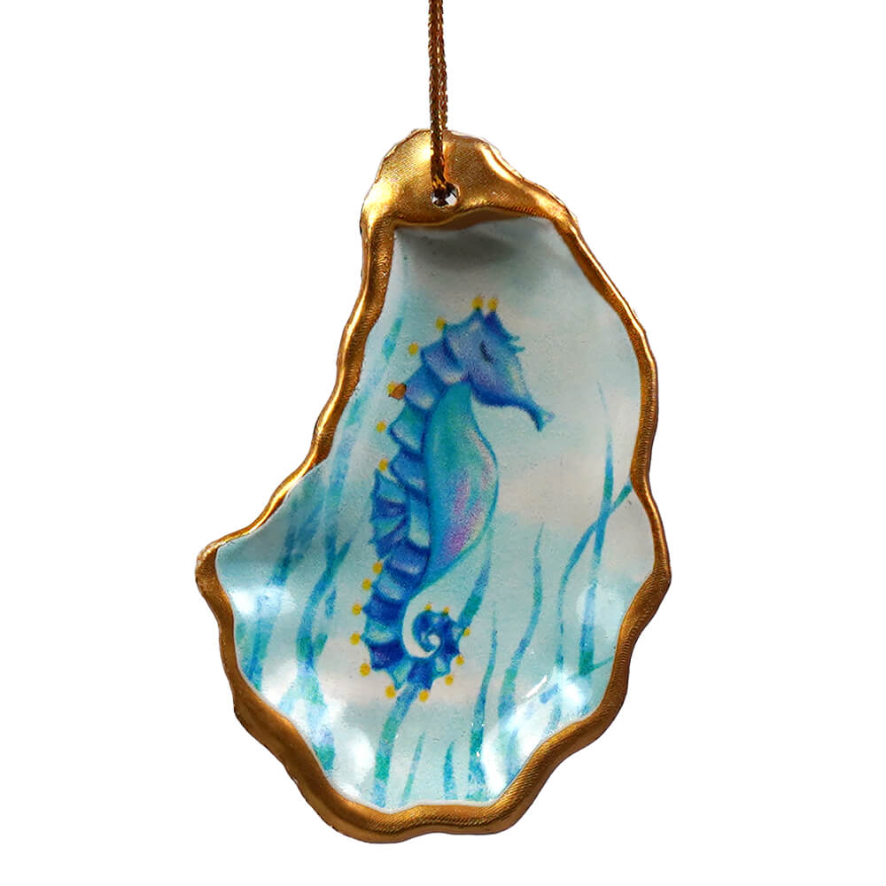 A hand-painted blue seahorse figural decor nestled in a gold-trimmed oyster shell from beachcombers set