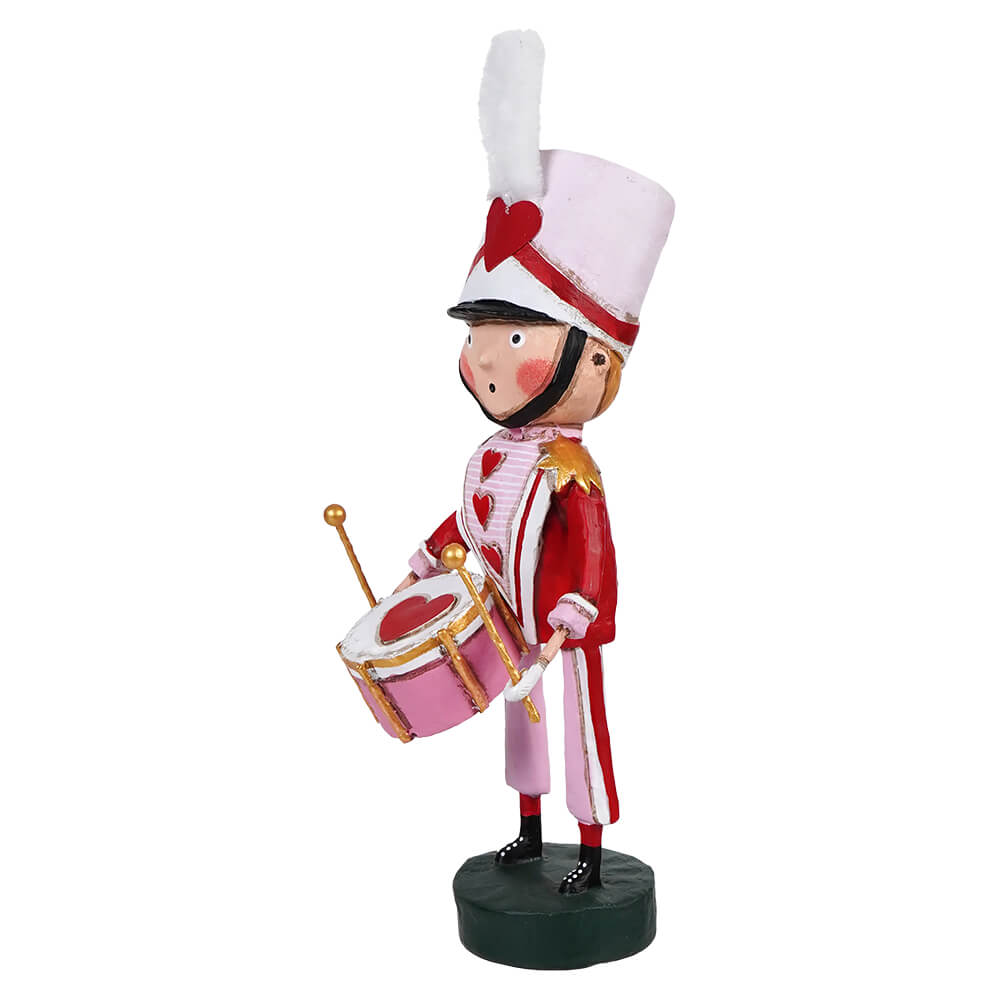 Decorative wooden nutcracker soldier figurine playing a drum in a red and white marching band uniform.