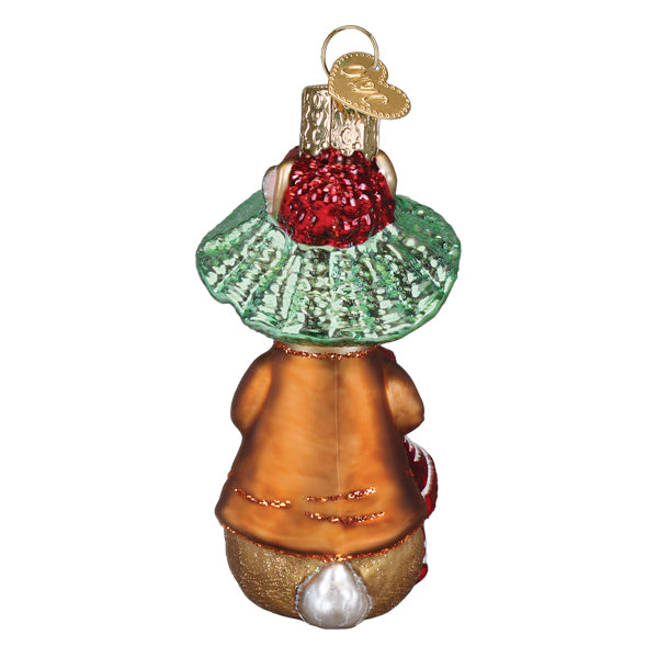 A glass christmas ornament featuring a whimsical rabbit in an orange coat with gold glitter trim, wearing a green ruffled collar and holding a red sparkly berry.